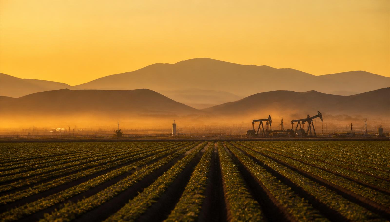 Kern County landscape at golden hour with farmland, oil pumpjacks, and distant mountains